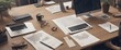 © RobRober - An aerial view shows a spacious, modern office workspace with various documents, laptops, a desktop computer, and a person working in the corner.