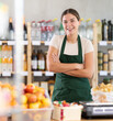 © JackF - Young female seller in apron standing at counter in grocery store