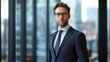 © Daiki - A young European male banker stands confidently in a modern office, wearing formal attire. This portrait captures professionalism and ambition in a sleek, urban setting.