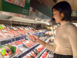 © Apichat - A woman is shopping for meat in a grocery store