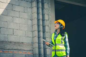 Wall Mural - Worker holds computer displaying construction plan while assessing project quality onsite.