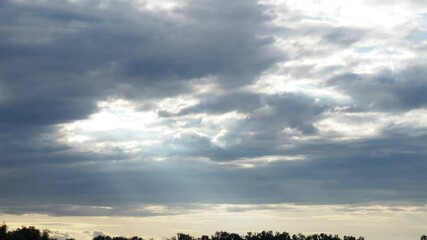 Poster - Witness the captivating journey of light slicing through layered clouds during twilight, showcasing natures artistry in a serene landscape. A transformative display unfolds overhead. Quick time lapse
