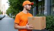 © Julia - Courier walking on a sidewalk with a package, friendly delivery man in an orange uniform working in the city.