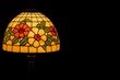 © SERHII - Stained glass lampshade with colorful floral design on dark background