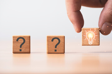 Poster - Hand holding glowing light bulb among question mark for creative thinking idea and problem solving solution concept.