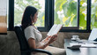 © Satori Studio - A woman sits by a window reading a book in a modern office, surrounded by greenery and natural light.