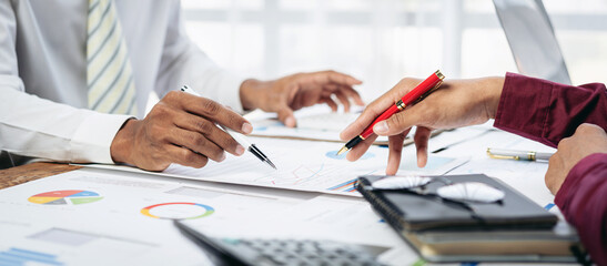 Fototapete - A man and a woman are sitting at a table with a red pen and a calculator