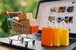 © Rifqi - Mini shopping cart with cardboard boxes on laptop, next to colorful shopping bags; online shopping concept for e-commerce, retail, and digital marketing