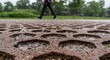 © Studio.no7 - Rainwater Harvesting: Close-up of Permeable Pavement with Water Droplets, Person Walking in Background. Sustainable Urban Drainage Systems for Stormwater Management and Green Infrastructure.