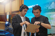 © Daniel Pawer - Asian male stage manager is discussing while pointing at clipboard, using headset and ID card, showing the coordination of work behind the scenes of the event with the stage atmosphere and LED screen.