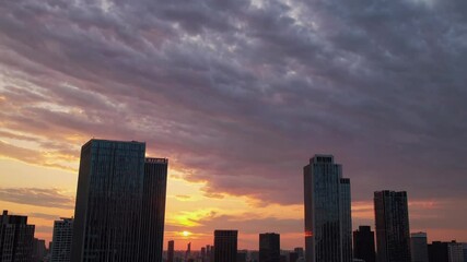 Aufkleber - Sunset over the skyline of a bustling city with tall buildings and dramatic clouds