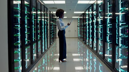 Leinwandbilder - Woman in business attire checking tablet while standing in a server room filled with glowing racks