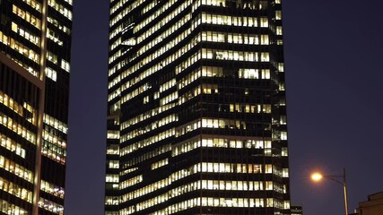 Poster - City skyline illuminated at night with buildings reflecting lights from offices in a busy urban area