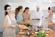 © JackF - Young lady who attends group class of culinary school cuts up chicken and prepares low-calorie diet lunch