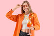 © Pixel-Shot - Young woman in sunglasses with aperol spritz cocktail on pink background