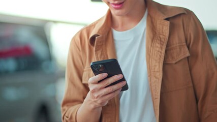 Close-up of asian man’s hands using smartphone while standing near shopping mall in city street – online communication, messaging, social media, and urban lifestyle with digital connection on the go