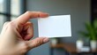 © Konstantin - Close-up hand with neat manicure holds blank white cardboard mock up business card on office background. Business and logo template