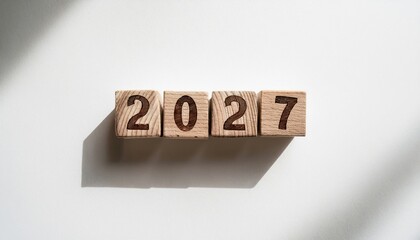 Poster - wooden number blocks forming 2027 casting sharp shadows on white textured paper in natural sunlight for minimal new year graphic, website banner, calendar, or editorial design

