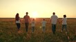 © Victoriia - Big active family in summer go on green grass in meadow. Parents children walking in summer nature park. Mom dad son daughter walk together at sunset. Family people kids walking on field holding hands