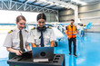 © unai - Female pilots using laptop and preparing flight plan in hangar