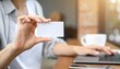 © photostockatinat - A hand presenting a blank business card while working on a laptop computer