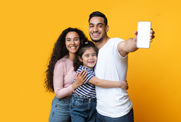 Aufkleber - Cheerful Arab Family Of Three Demonstrating Blank Smartphone With White Screen, Loving Middle Eastern Mom, Dad And Little Daughter Embracing And Enjoying New Mobile Application Or Website, Mockup