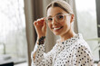 © Maria Vitkovska - Smiling happy businesswoman adjusting glasses in modern office