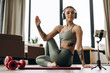 © Maria Vitkovska - Fitness influencer practicing yoga online using smartphone and headphones