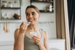 © Maria Vitkovska - Young smiling beautiful woman eating yogurt in modern kitchen after workout