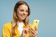 © Maria Vitkovska - Happy young woman using a smartphone and smiling on a blue background