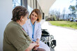 © Halfpoint - Doctor and elderly patient sitting in front of hospital building and talking.
