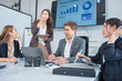 © panomporn - Group of business partners gathered around open laptop discussing company development strategies in modern office.
