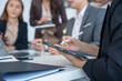 © panomporn - Group of business partners gathered around open laptop discussing company development strategies in modern office.
