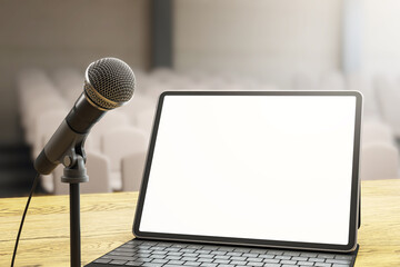 Poster - Microphone and laptop with blank screen on wooden stage desk in empty auditorium with soft background lighting during workshop setup scene. 3D Rendering