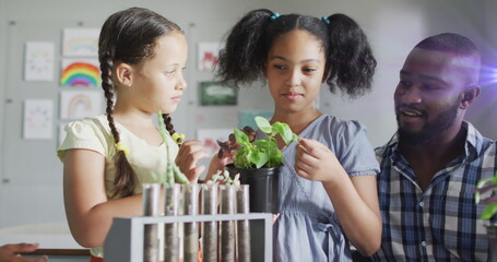 Poster - Image of light trails over diverse schoolchildren and teacher holding plants