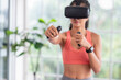 © weedezign - Asian woman wear virtual reality glasses and train boxing with joystick control at home