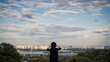 © Bohdan - Woman in Hat Looking at City Skyline from Hilltop Viewpoint