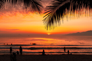 Wall Mural - Morning landscape in the rays of dawn sunrise over the ocean and the beach with people swimming relaxing