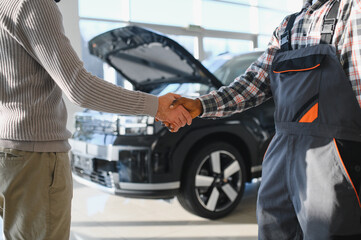 Fototapete - Mechanic, car servicing at garage - concept of timely customer service, car maintenance and deal agreemnet
