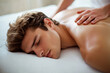 © TENphoto - Relaxing man receiving a massage in a spa environment