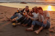 © bernardbodo - Friends toasting with bottles, enjoying sunset on beach