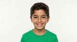A young boy with brown hair and eyes smiles brightly while wearing a green shirt against a white background.