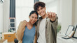 © tirachard - Young happy Asian sweet couple hugging each other smiling looking at camera show proud show off new house keychain in living room. Husband wife move new home, Apartment Rent And Ownership Concept.