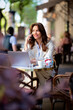 © sepy - Attractive woman sitting in an outdoor cafe and using computer laptop and smart phone