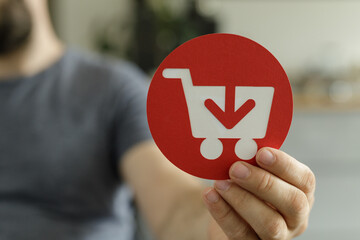 Aufkleber - Person holding a red circle with a shopping cart and download arrow icon.  E-commerce, online purchase.