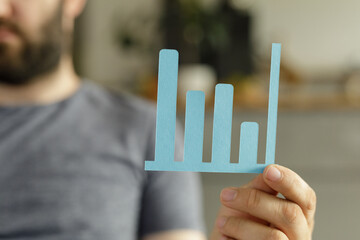 Poster - Stock photo of a man holding a bar graph, illustrating business growth and data analysis.