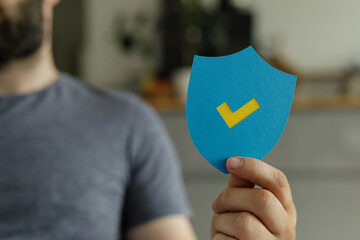 Poster - Image of a person holding a blue shield with a yellow checkmark, representing security and approval.