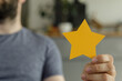 © vegefox.com - Stock photo of a man holding a golden star, representing customer satisfaction, feedback, and positive review.