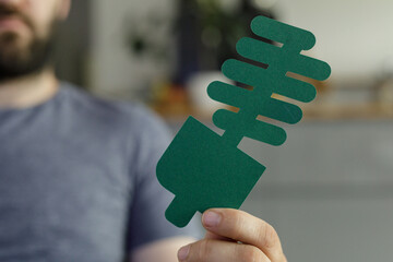Aufkleber - Image of a person holding a green paper cut-out of a shock absorber, symbolizing eco-friendly car parts.