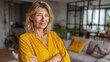 © Ірина Пальцева - Confident woman in bright yellow shirt with arms crossed. Calmly facing the camera in her modern home. Positive attitude and relaxed lifestyle.
